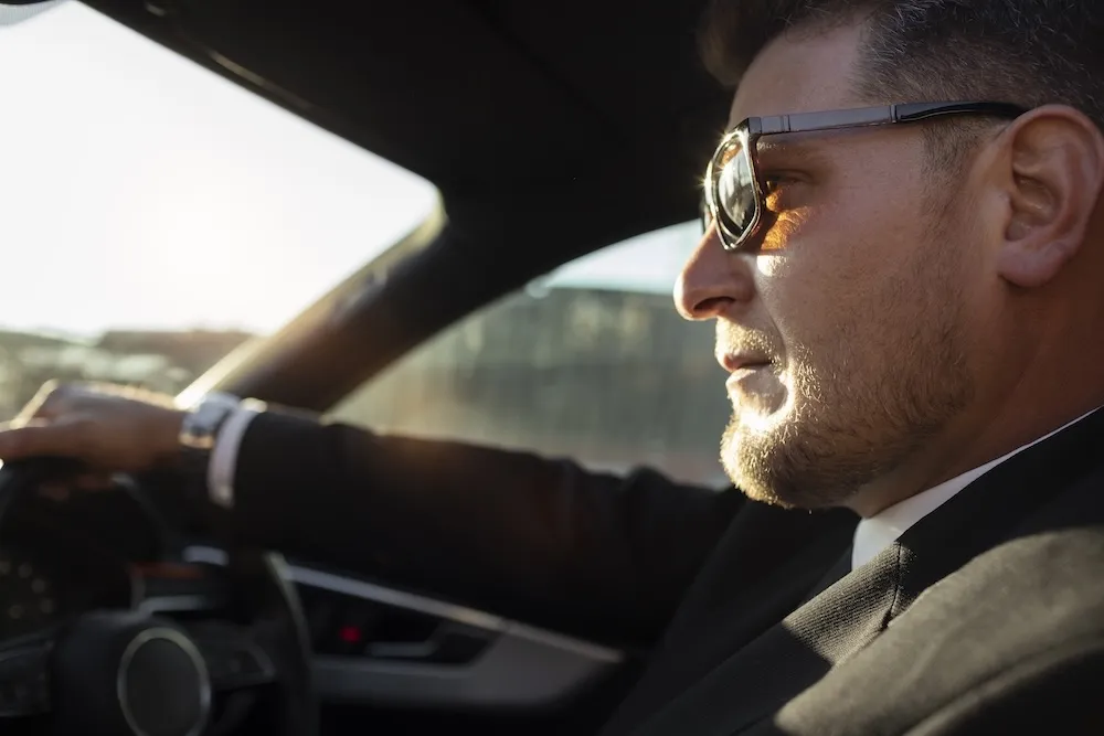 Professional chauffeur in a suit driving an executive car during an hourly business chauffeur hire in London