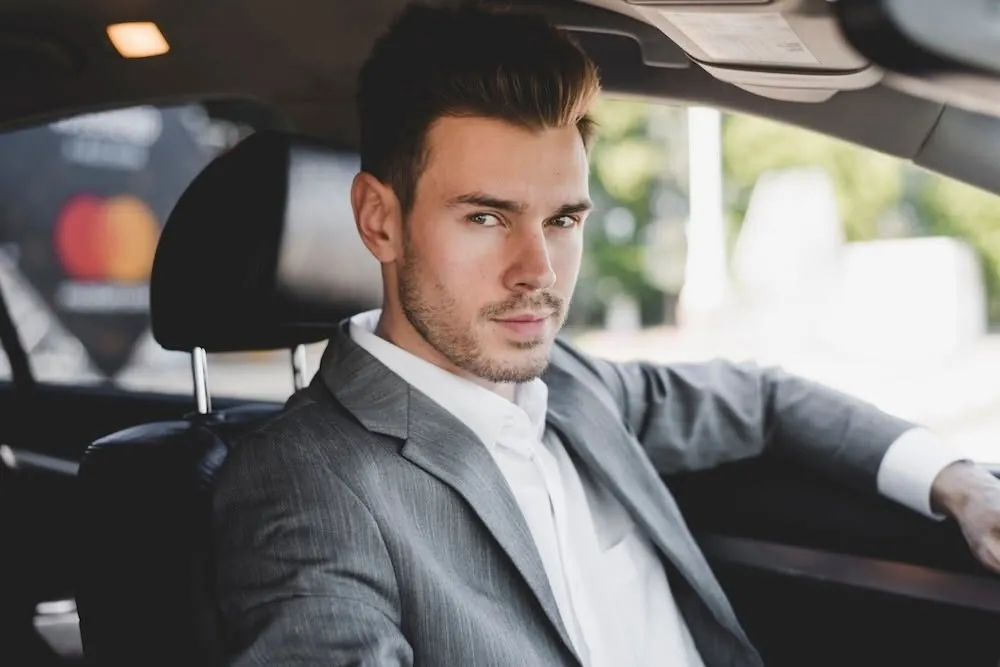 Smartly dressed passenger sitting comfortably in the back of a chauffeur-driven car, enjoying a stress-free journey