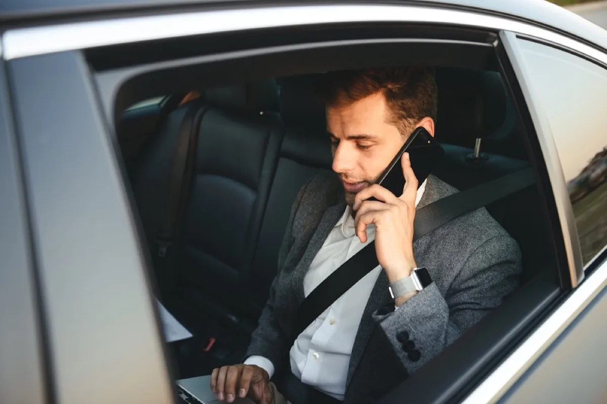 Businessman taking a call in the back of a chauffeur-driven car in London — executive chauffeur hire