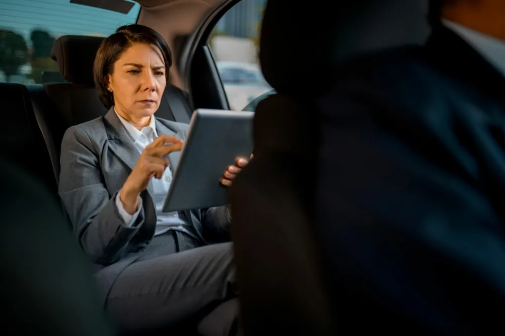 Businesswoman relaxing with a tablet in the back seat of a luxury car during a chauffeur sightseeing tour of London