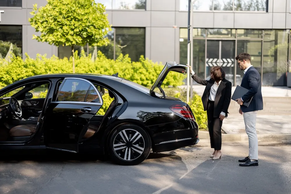 Professional chauffeur assisting a client beside a luxury Mercedes S-Class on a private chauffeur tour of London